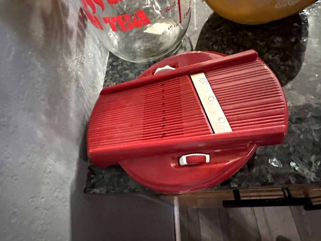 Red mandoline slicer and glass pitcher